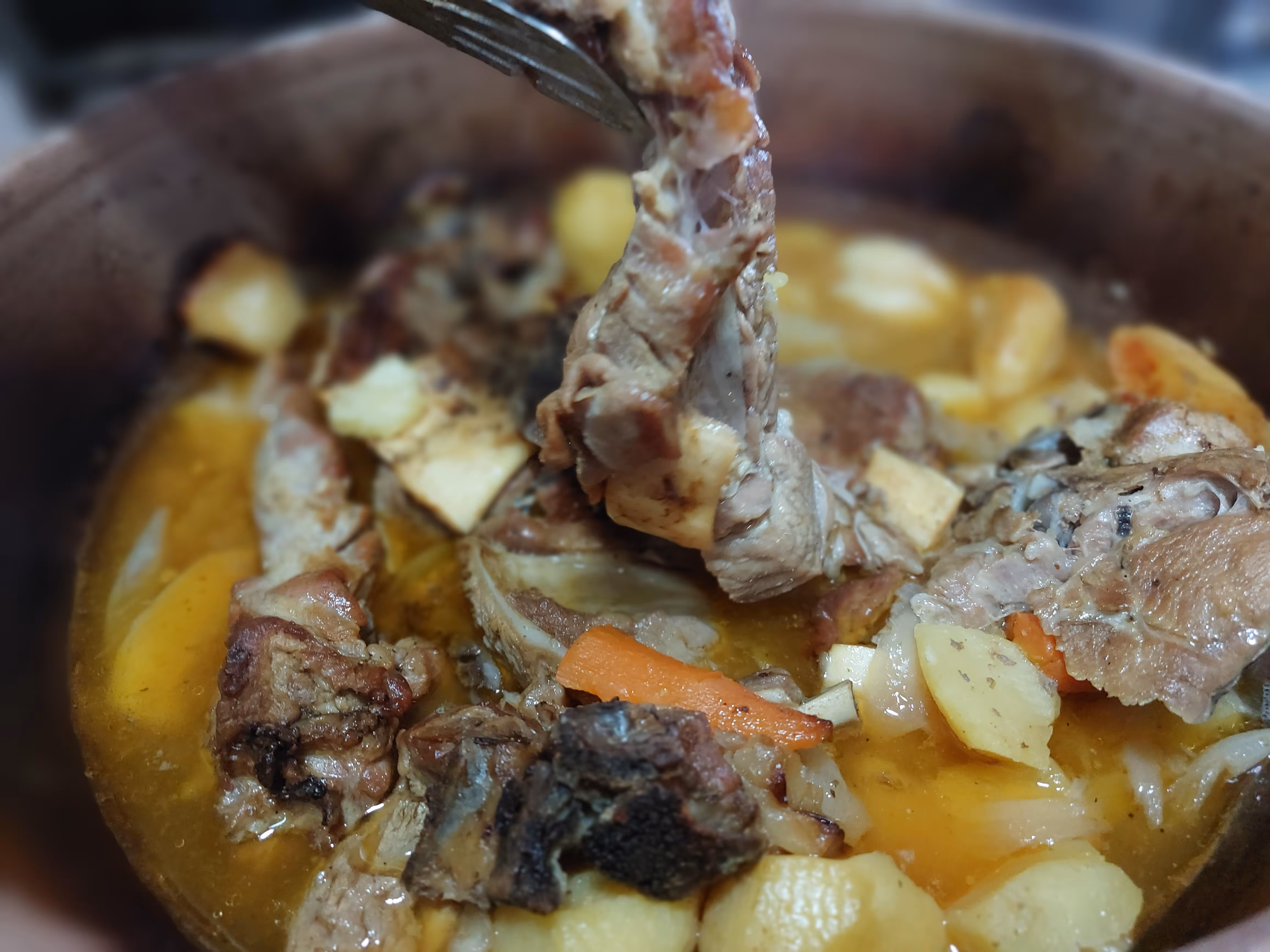 Close-up of a hearty stew with chunks of meat, potatoes, carrots, and onions in a rich broth.